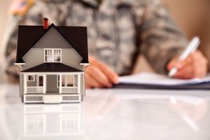 Service member wearing Army uniform (ACU) filling real estate related paperwork.